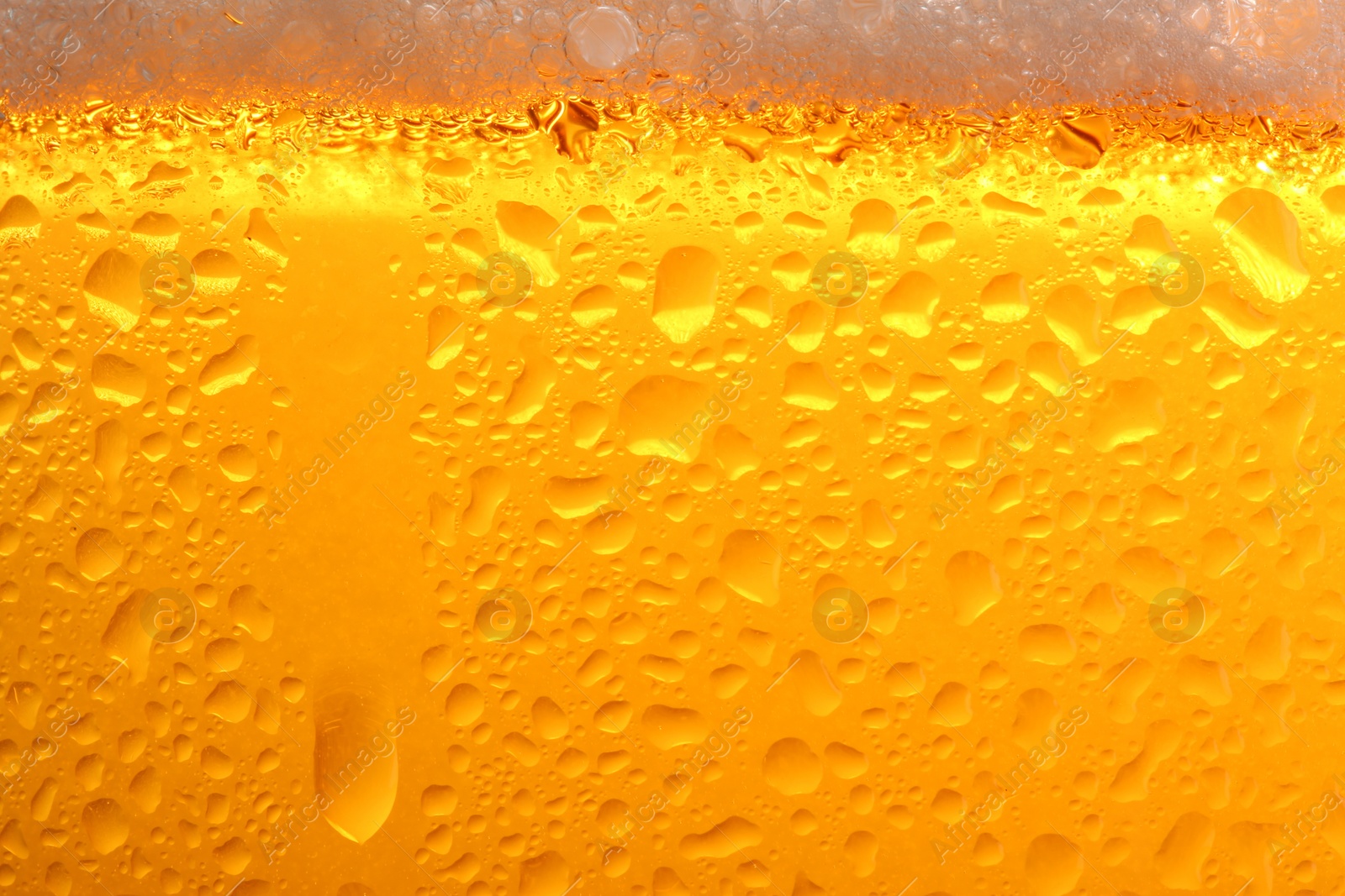 Photo of Glass of tasty cold beer with foam and condensation drops as background, closeup