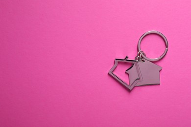 Photo of Metallic keychains in shape of houses on bright pink background, top view. Space for text
