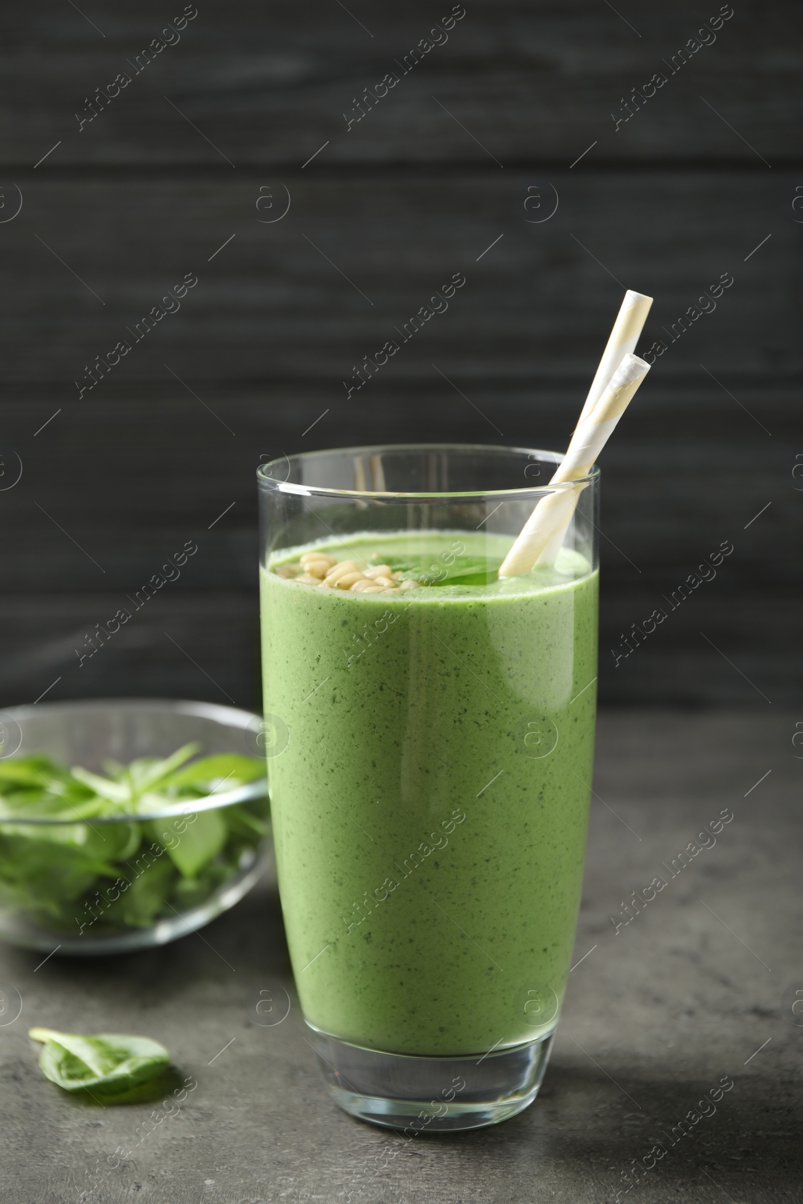 Photo of Glass of healthy green smoothie with fresh spinach on grey table