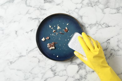 Photo of Woman washing dirty plate at white marble table, top view