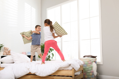 Happy children having pillow fight in bedroom