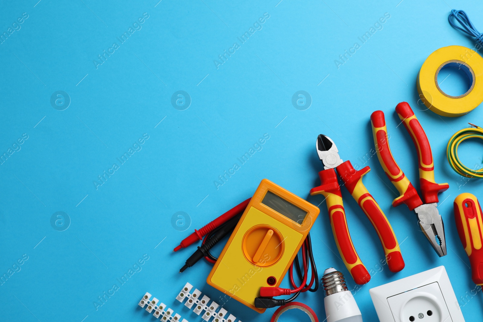 Photo of Flat lay composition with electrician's tools and accessories on light blue background, space for text