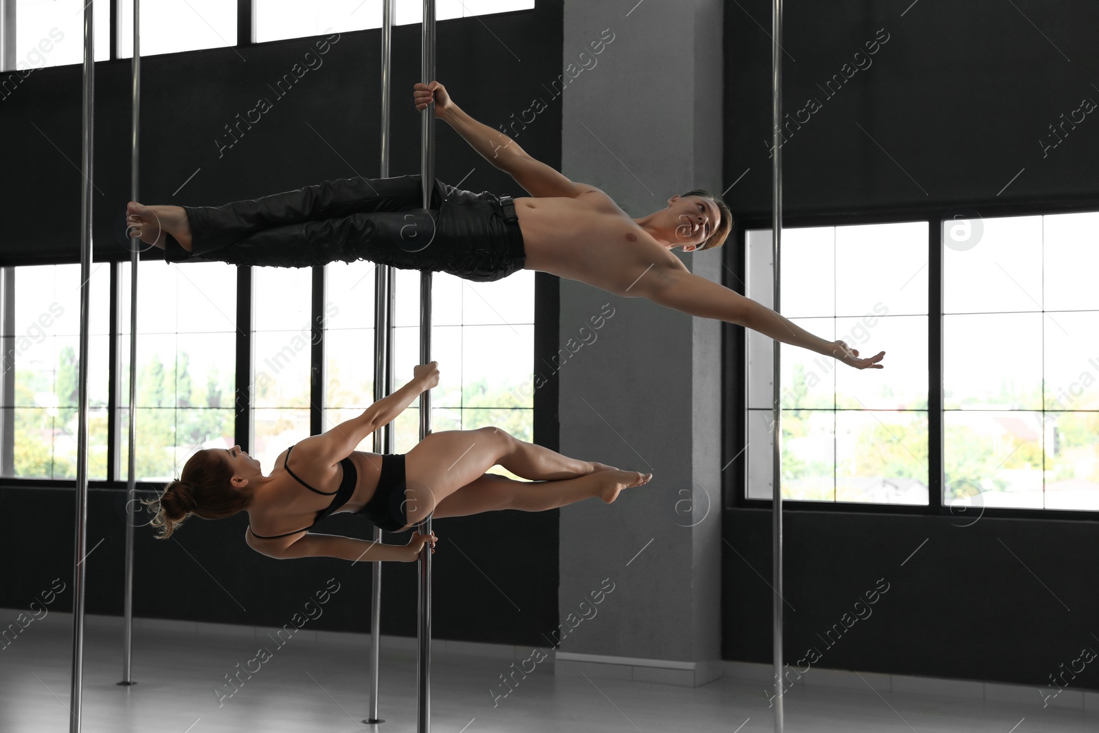 Photo of Young couple dancing in studio with poles