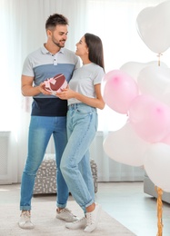 Photo of Young couple in room decorated with air balloons. Celebration of Saint Valentine's Day