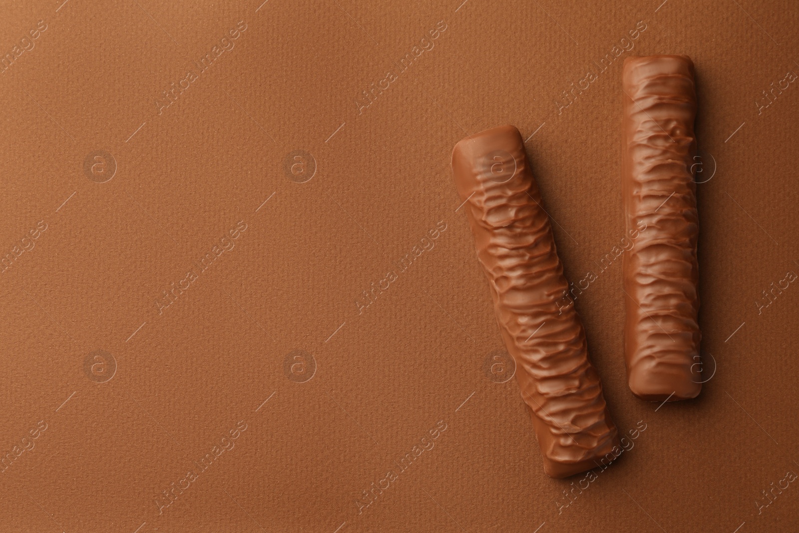 Photo of Sweet tasty chocolate bars on brown background, flat lay. Space for text