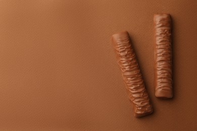 Photo of Sweet tasty chocolate bars on brown background, flat lay. Space for text
