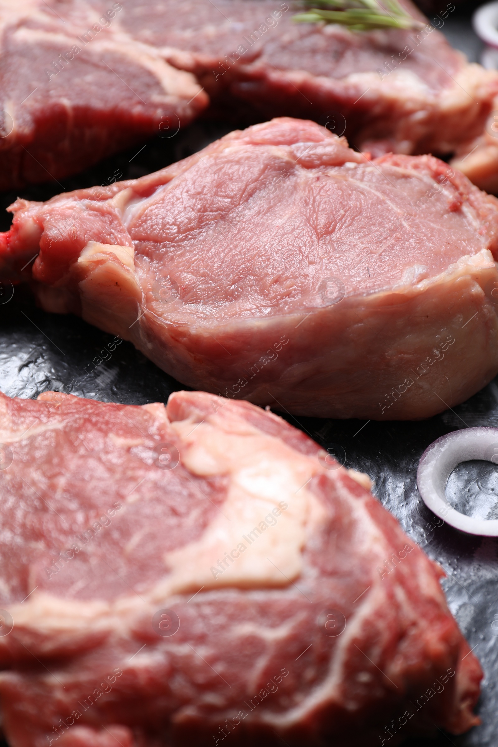 Photo of Fresh raw beef cuts and onion ring on table, closeup