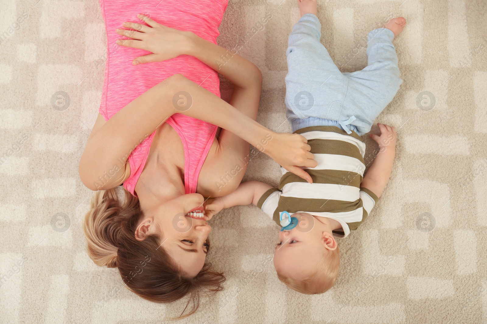 Photo of Young woman with her son lying on floor at home, top view