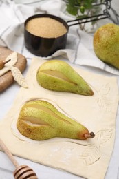 Photo of Raw dough with fresh pears on white table, closeup