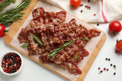 Photo of Slices of tasty fried bacon with different spices and tomatoes on light table, flat lay