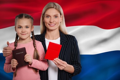 Image of Immigration. Happy woman and her daughter with passports against national flag of Netherlands, space for text