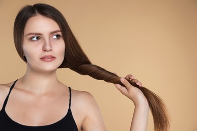 Photo of Young woman with strong healthy hair on beige background, space for text