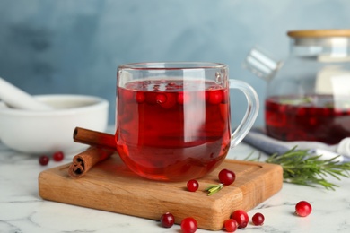 Photo of Tasty hot cranberry tea and fresh ingredients on white marble table