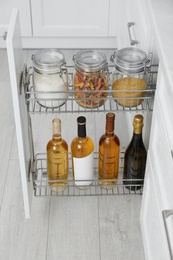 Photo of Open drawer with jarsfood and wine bottles in kitchen