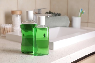 Photo of Fresh mouthwashes in bottles on countertop in bathroom, closeup. Space for text