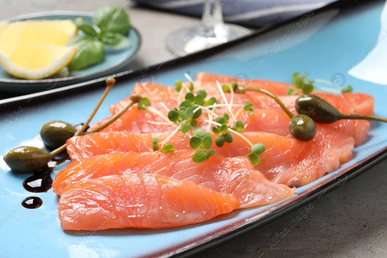 Photo of Delicious salmon carpaccio served on light grey table, closeup