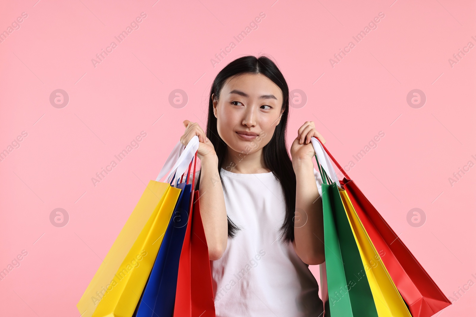 Photo of Beautiful woman with shopping bags on pink background. Space for text