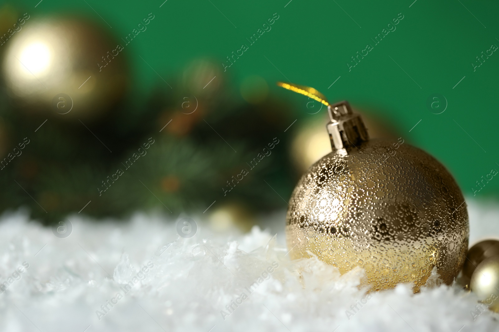 Photo of Beautiful Christmas balls on snow against green background. Space for text