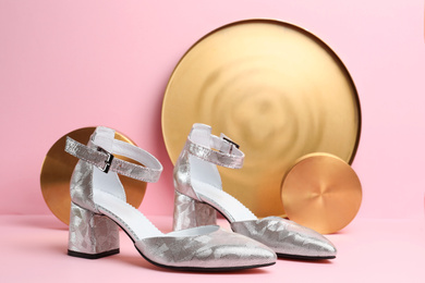 Photo of Stylish silver female shoes and decor on pink background
