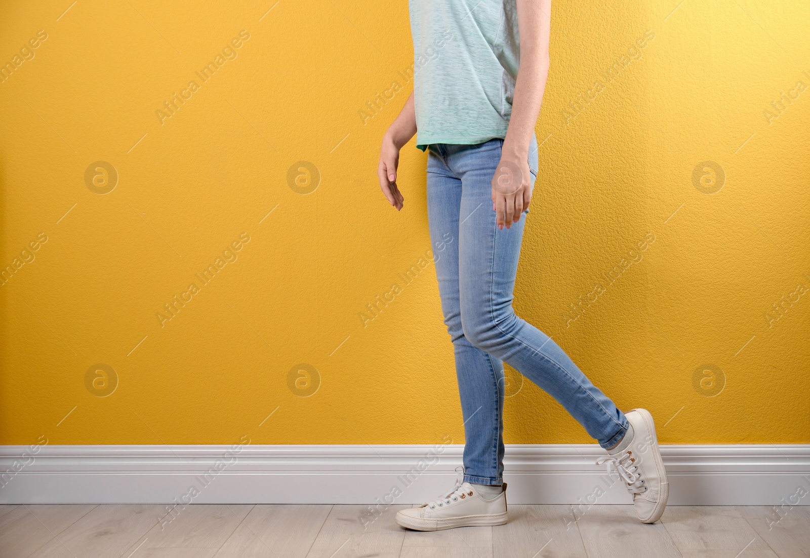 Photo of Young woman in stylish jeans near color wall