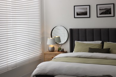 Photo of Window with horizontal blinds and comfortable bed in room