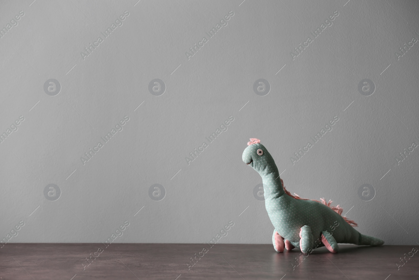 Photo of Abandoned toy dinosaur on table against light background. Time to visit child psychologist