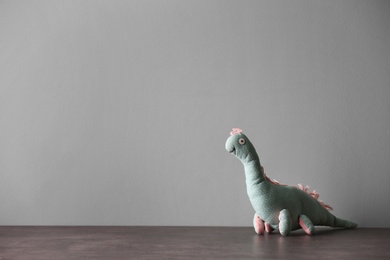 Photo of Abandoned toy dinosaur on table against light background. Time to visit child psychologist