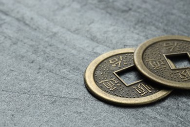 Photo of Chinese coins on grey textured table, closeup. Space for text