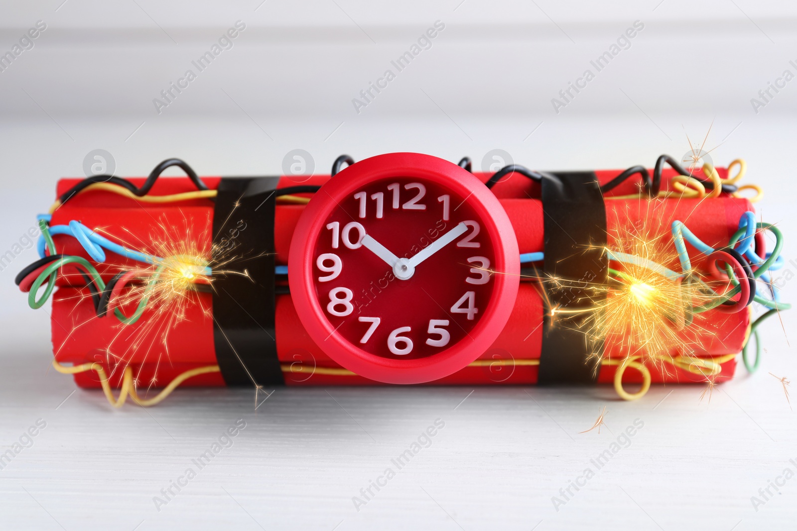 Image of Dynamite time bomb with burning wires on white wooden table