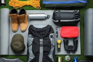 Photo of Flat lay composition with different camping equipment on green grass