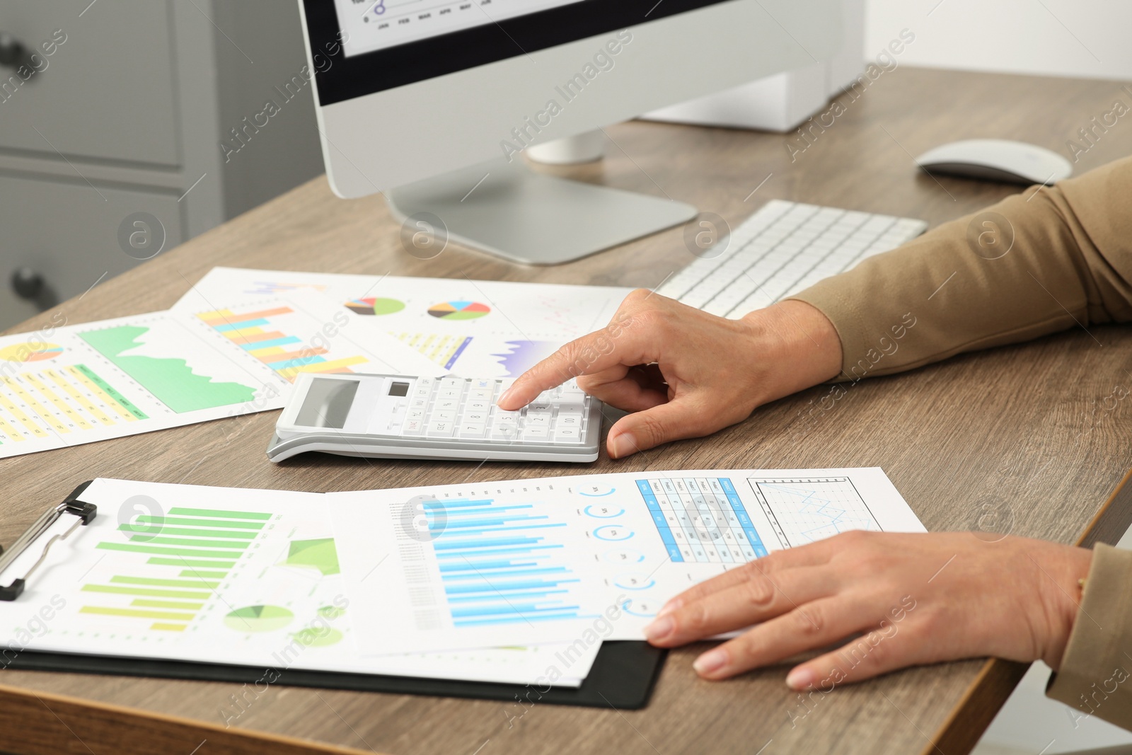 Photo of Accountant using calculator at wooden desk in office, closeup