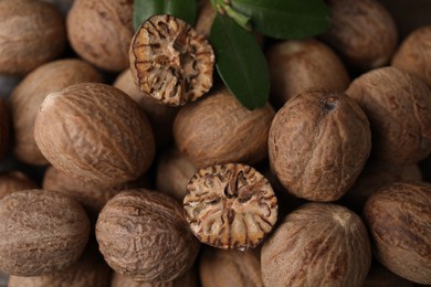 Photo of Whole and cut nutmegs as background, top view