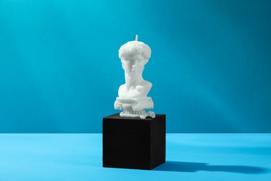 Photo of Stylish presentation of David bust candle on light blue background