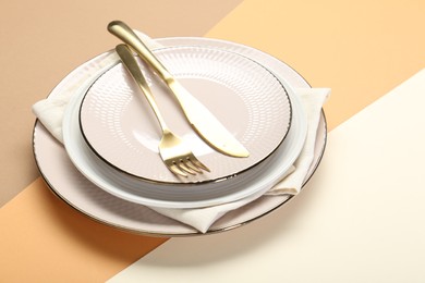 Ceramic plates, cutlery and napkin on color background. Space for text