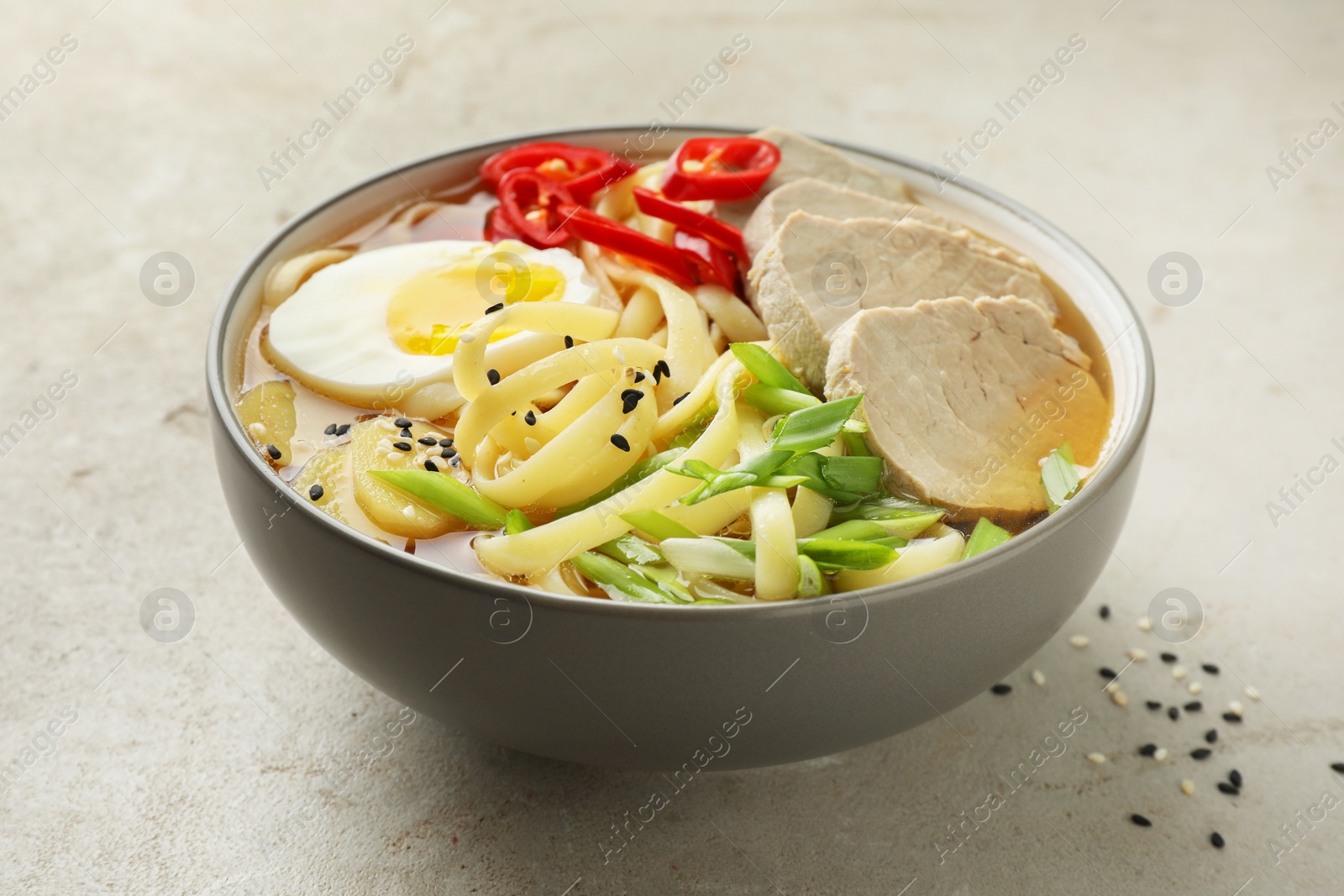 Photo of Delicious ramen in bowl on light textured table, closeup. Noodle soup