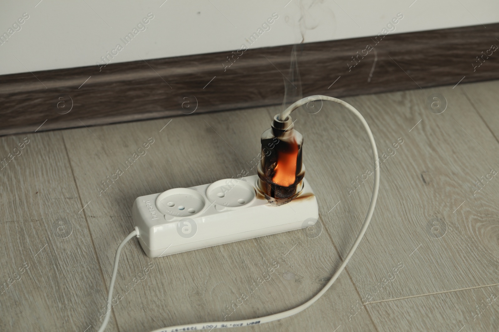 Photo of Inflamed plug in power strip indoors. Electrical short circuit