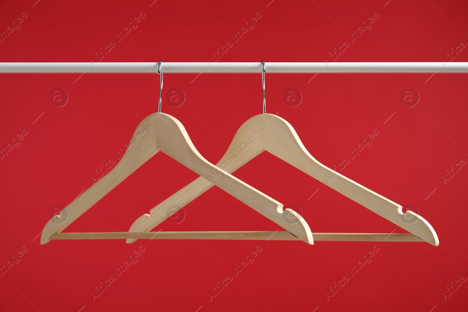 Photo of Empty clothes hangers on rack against red background