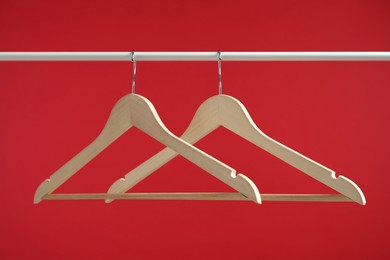 Photo of Empty clothes hangers on rack against red background