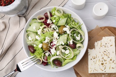 Bowl of tasty salad with leek, olives and cheese on white textured table, flat lay