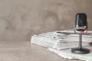 Newspapers and vintage microphone on marble table, space for text. Journalist's work
