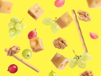 Image of Cheese, breadsticks, grapes and walnuts falling against yellow background