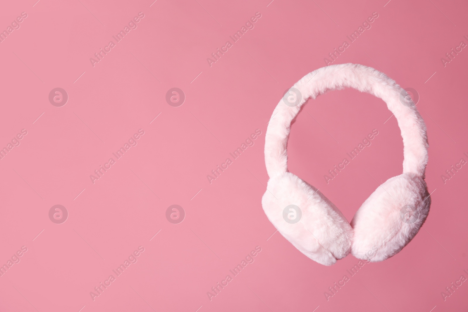 Photo of Stylish winter earmuffs on pink background, space for text