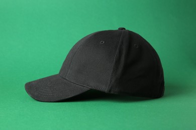 Photo of Stylish black baseball cap on green background