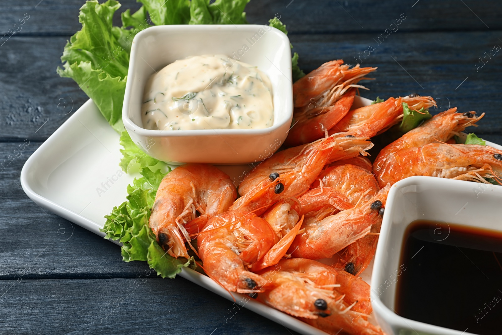 Photo of Plate with juicy shrimps and sauces on table, closeup