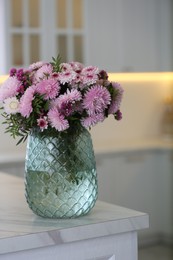 Photo of Vase with beautiful chrysanthemum flowers on table in kitchen. Interior design