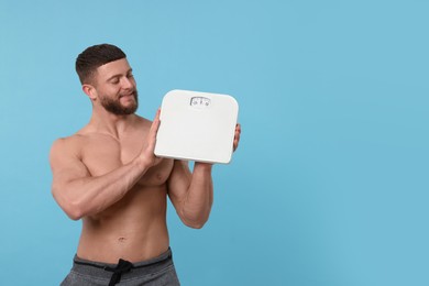 Photo of Athletic man holding scales on light blue background, space for text. Weight loss concept