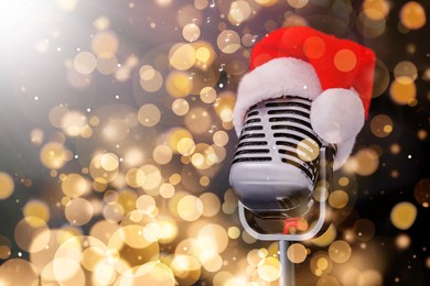 Image of Retro microphone with Santa hat against blurred lights, space for text. Christmas music. Bokeh effect