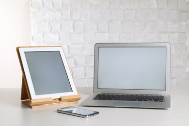 Photo of Modern laptop, tablet and smartphone on table indoors. Space for design