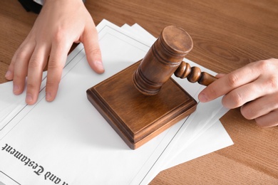 Male notary with gavel and documents at wooden table, closeup