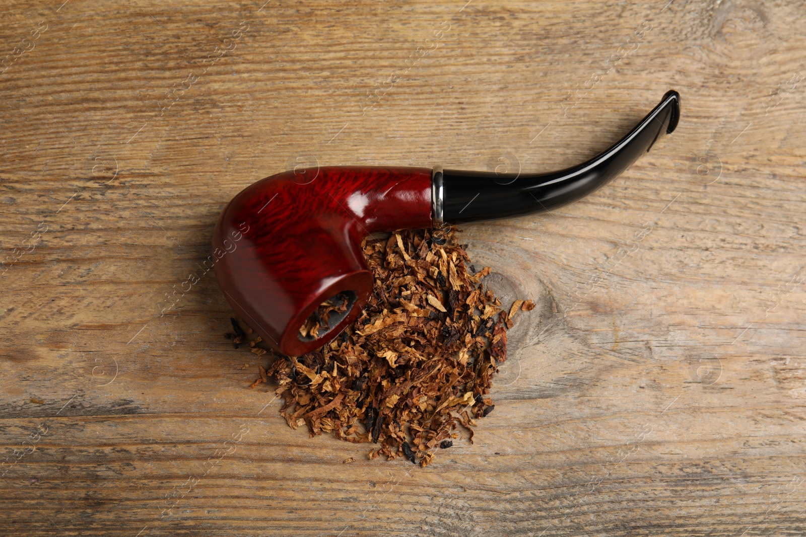 Photo of Smoking pipe with tobacco on wooden table, above view